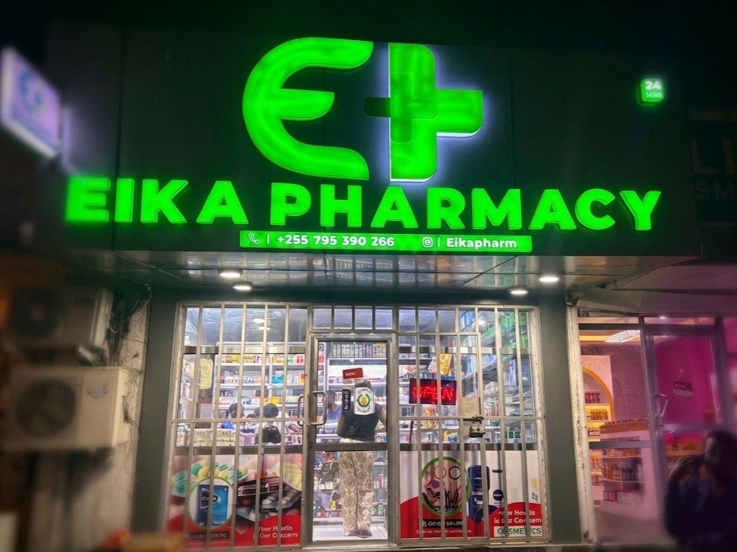 The EIKA PHARMACY shopfront lit up at night, with the 24 HRS sign glowing beside the entrance
